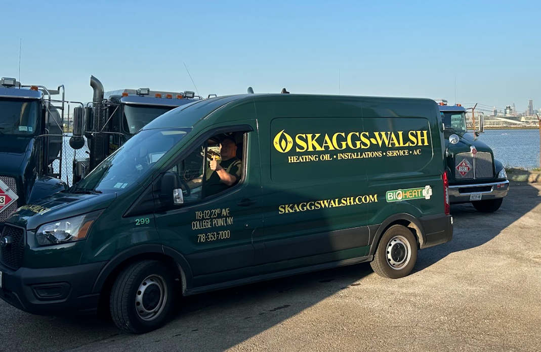 Skaggs-Walsh service van in front of a fleet of delivery trucks for heating oil delivery in Nassau County.